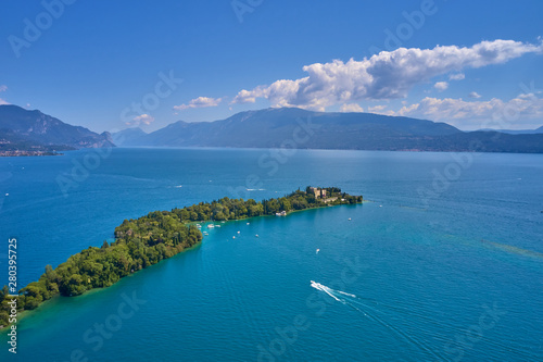 Fototapeta Naklejka Na Ścianę i Meble -  Unique view of the island of Garda. In the background is the Alps. Resort place on Lake Garda north of Italy. Aerial photography with drone.