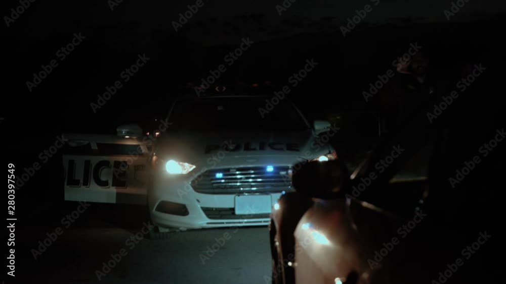 Amazing night scene. Police on duty. Side view of professional traffic cops detaining and arresting drunk driver. Close-up policeman leading scared young man to the car hood to handcuff him. Amazing night scene. Police on duty. Side view of professional traffic cops detaining and arresting drunk driver. Close-up policeman leading scared young man to the car hood to handcuff him.