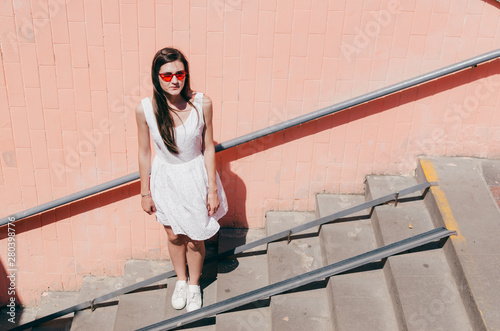 Girl in pink sunglases Standing Up Against Bright Pink Wall photo