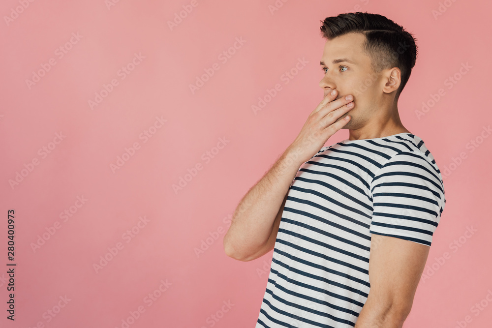 shocked young man in striped t-shirt covering mouth with hand isolated on pink shocked young man in striped t-shirt covering mouth with hand isolated on pink