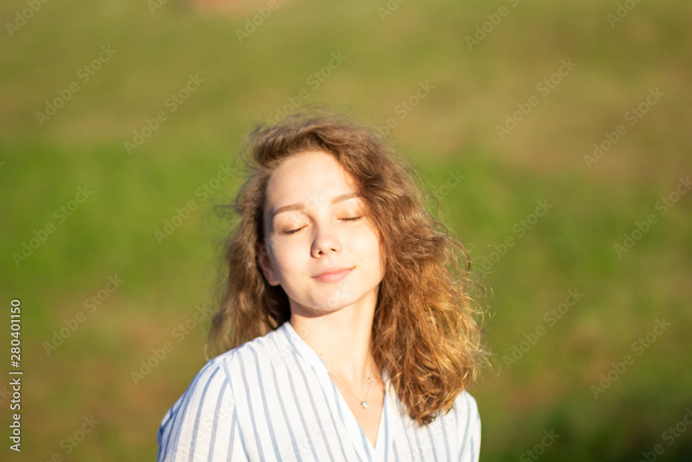 Portrait of beautiful young woman with closed eyes in the summer park