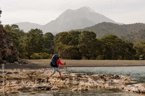 Woman with backpack trekking on a sea shore photo