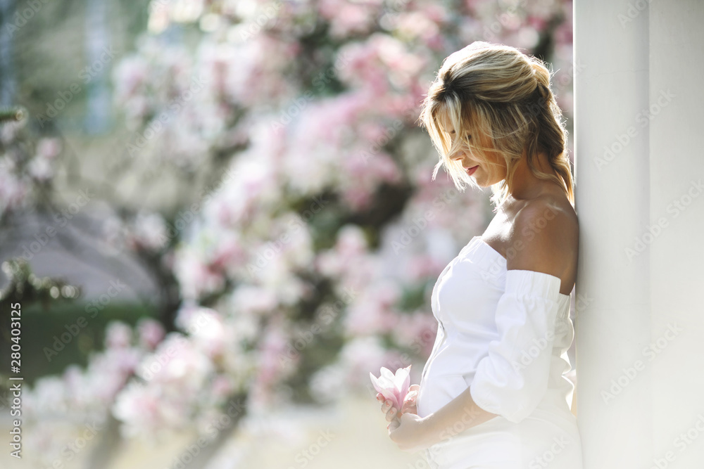 pregnant woman in a white dress standing near the wall pregnant woman in a white dress standing near the wall