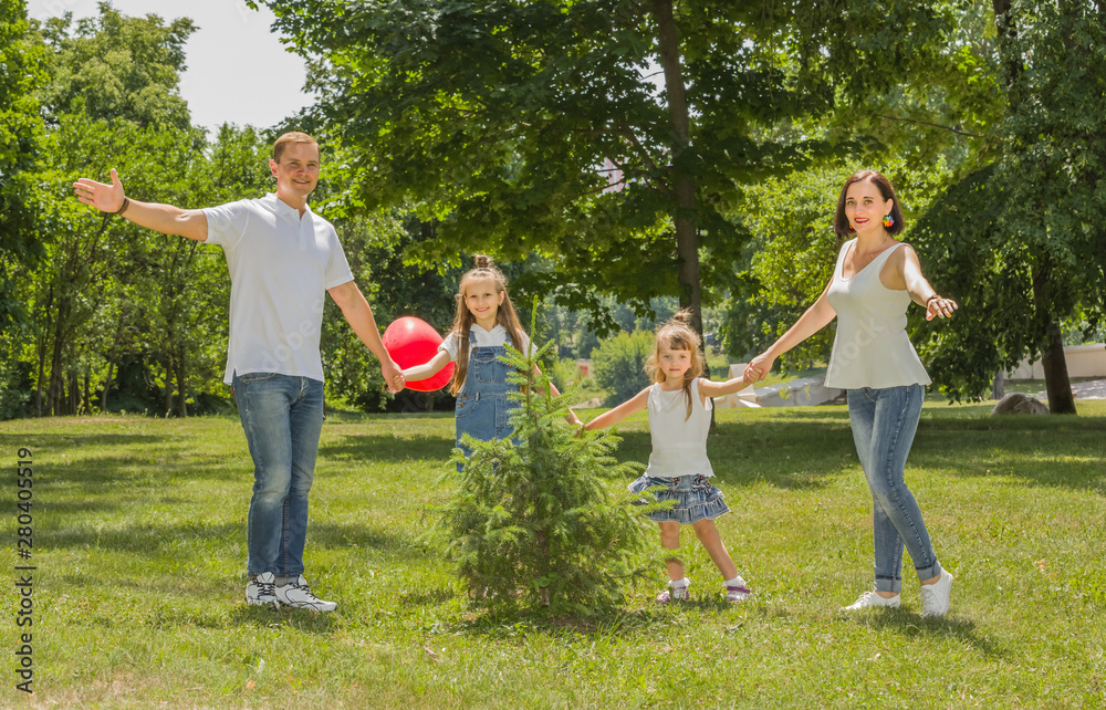 Obraz premium Szczęśliwa rodzina obchodzi jodłę w letnim ogrodzie