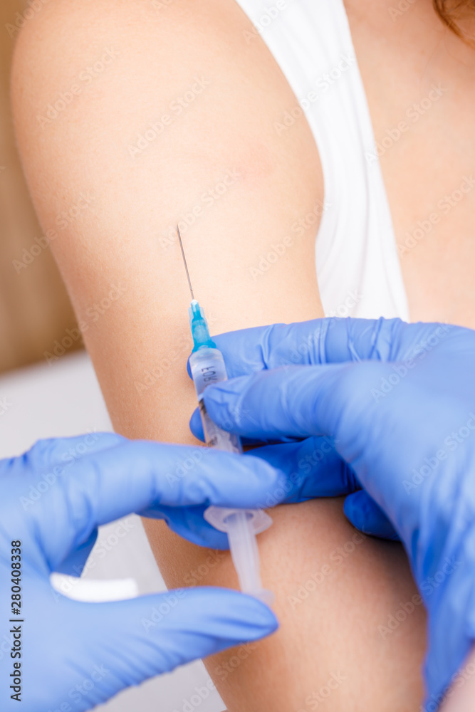 Doctor injecting a vaccine in arm close-up Doctor injecting a vaccine in arm close-up