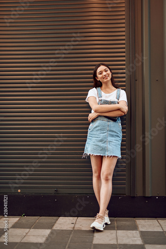 Young happy asian lady leaning on wall on street