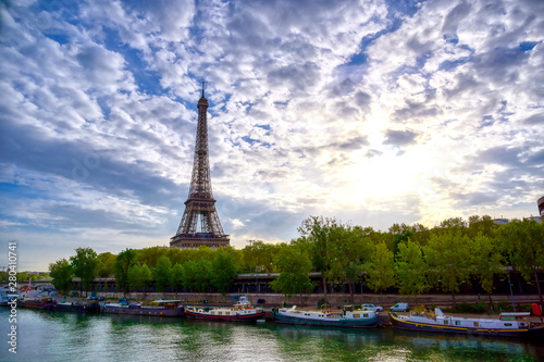 The Eiffel Tower across the Seine River in Paris, France on a sunny day with beautiful clouds. © Jbyard