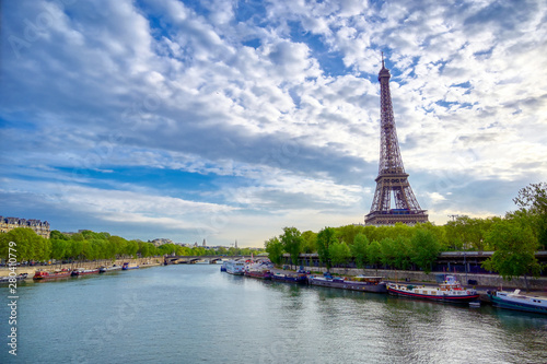 The Eiffel Tower across the Seine River in Paris, France on a sunny day with beautiful clouds. © Jbyard