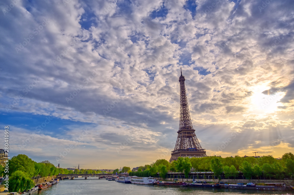 The Eiffel Tower across the Seine River in Paris, France on a sunny day with beautiful clouds.