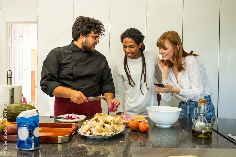 chef teaching a young couple of different breeds how to cook chef teaching a young couple of different breeds how to cook
