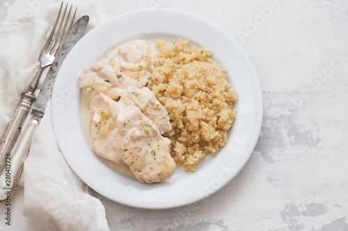 dish of meat with sauce and boiled quinoa on white wooden background