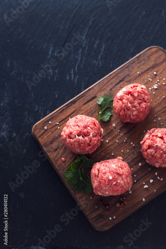 raw meatballs with pepper and salt on wooden board