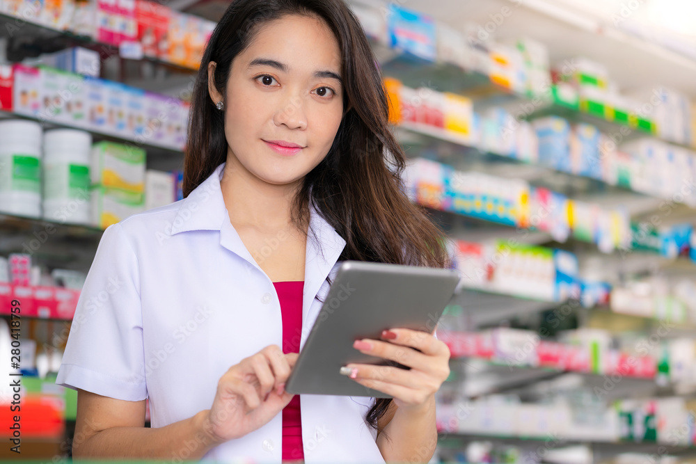 Asian female pharmacist uses digital tablet in the pharmacy