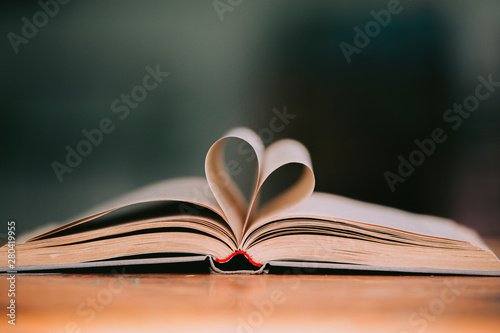 Old book page decorate to heart shape for love in valentine day with blurred background and vintage color tone style. Composition of love with open book heart, Love of books, Library, education.