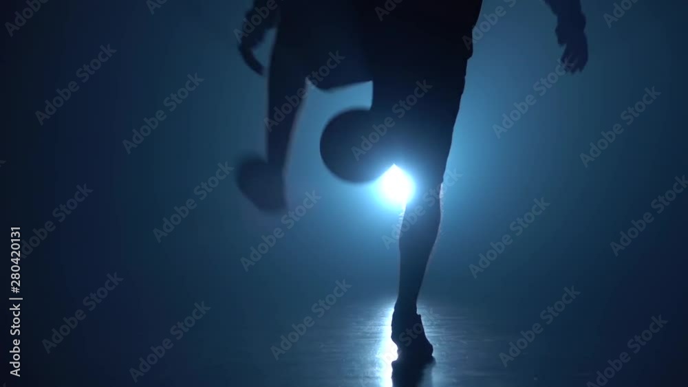 Soccer player's legs stuffing ball in twilight. Slow motion