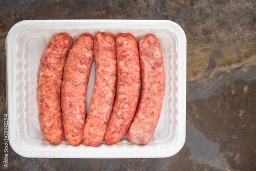 Fresh Raw Sausages in White Plastic Container Top View Close Up, Copy Space