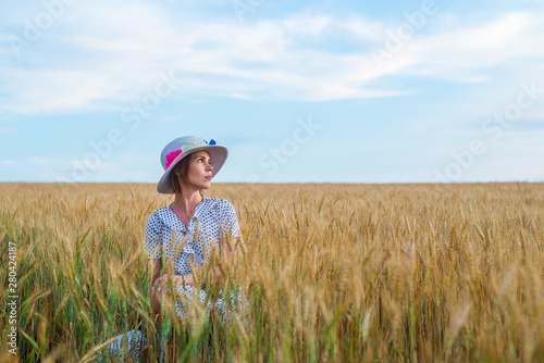 Free and happy woman in dress and hat on wheat field. Freedom, joy concept. © Konstiantyn Zapylaie