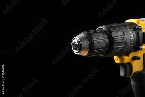 Electric drill closeup on a black background with wood and drills. Electrical tools. Hand battery screwdriver.
