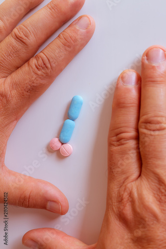 Hands of a man next to pills that symbolize a penis with an erection. Metaphor of male virility. Medicine related to male impotence.