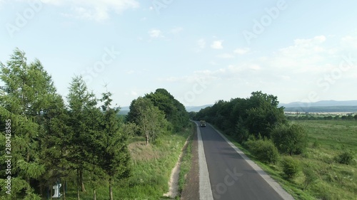 Aerial shot of a truck on the road in beautiful countryside in the summer.