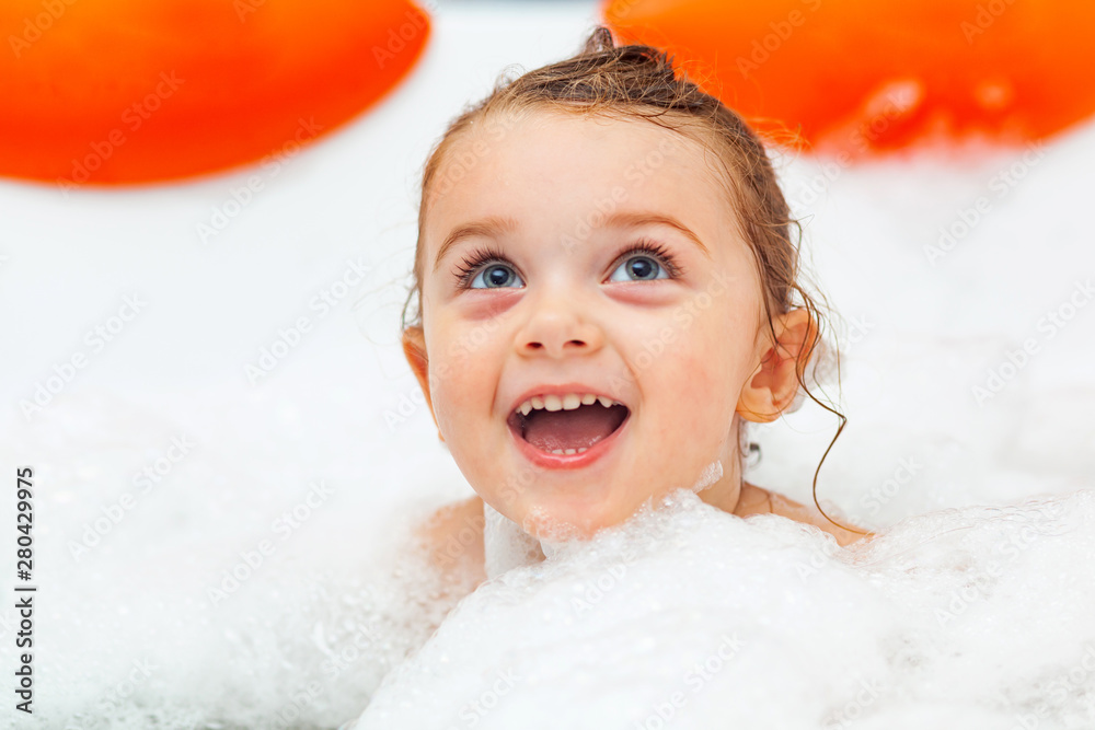 Little girl takes a bath in a hydromassage bathtub. Stock Photo Adobe