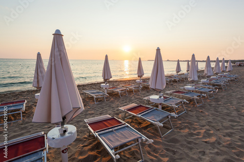 Closed umbrellas and chairs at beautiful sunset. © Antonio Gravante