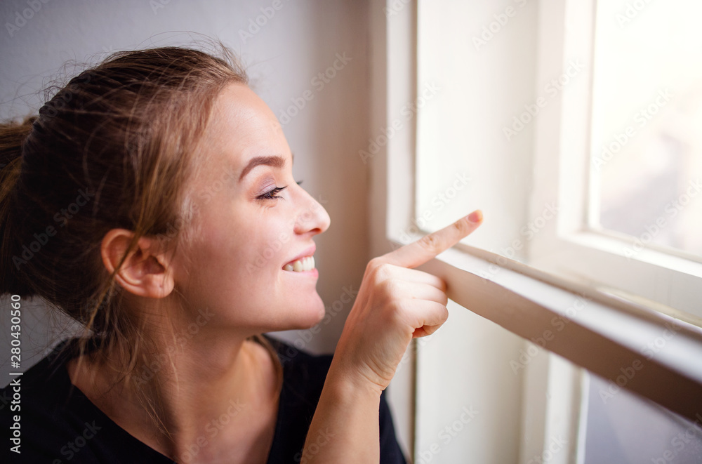 Close-up of young happy female student sitting on window sill. Close-up of young happy female student sitting on window sill.