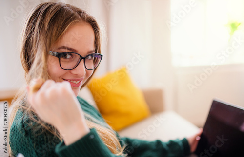 A young female student sitting on sofa, using laptop when studying.