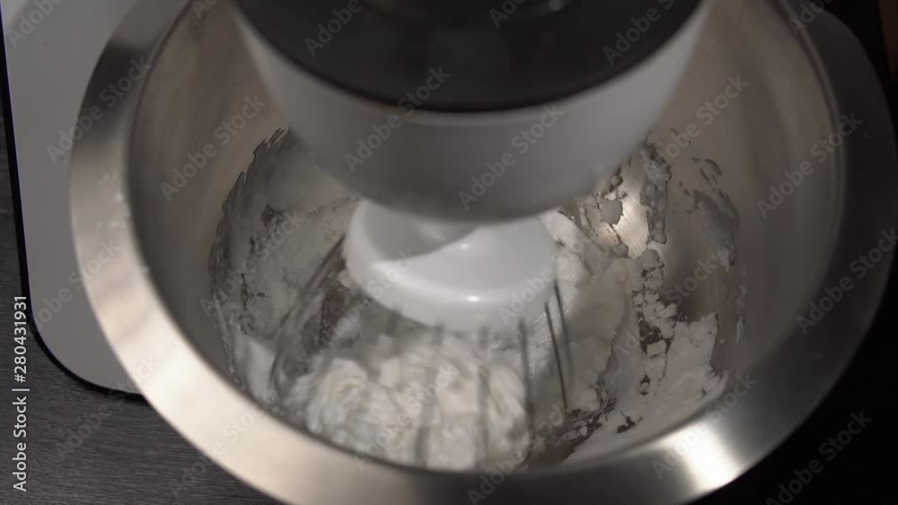 Top view of a food processor with whisk whipping cream in stainless steel bowl. Top view of a food processor with whisk whipping cream in stainless steel bowl.