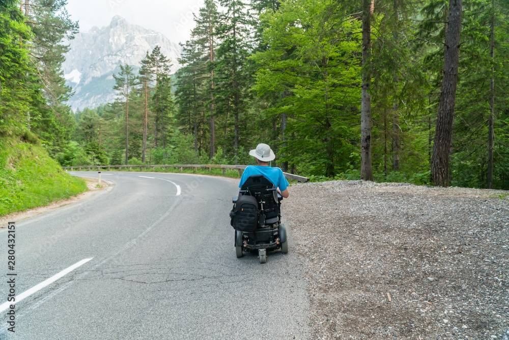 disabled person in an electric wheelchair driving on the street, road disabled person in an electric wheelchair driving on the street, road
