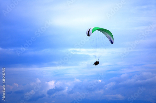 Paraglider flying in the blue sky with beautiful clouds.
