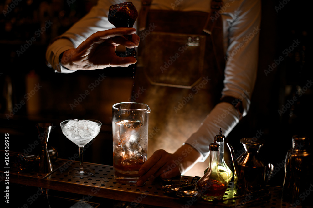 Bartender pouring a cocktail from vial in glass