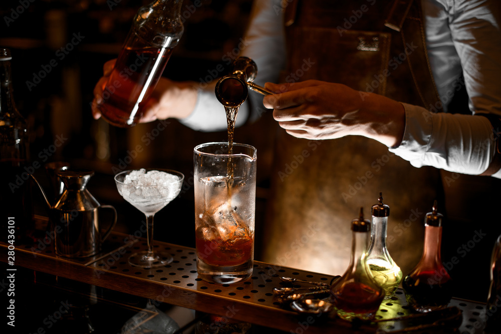 Bartender preparing alcohol cocktail using jigger with handle