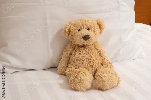 Cute teddy bear portrait in bed, sitting on the white pillow