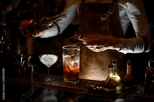 Bartender prepares an alcohol cocktail using jigger