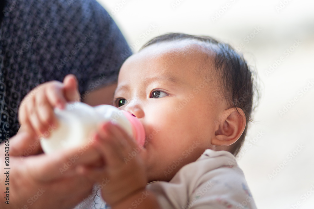 Asian baby girl sucking milk from bottle, Kid drinking milk Asian baby girl sucking milk from bottle, Kid drinking milk