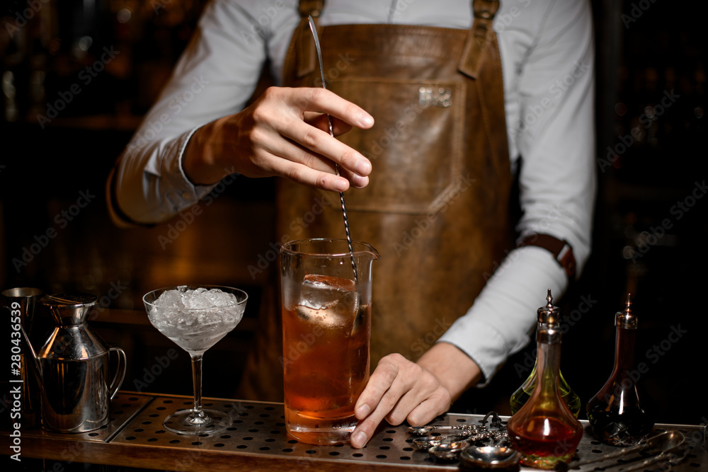 Bartender stirs alcohol drink with a spoon