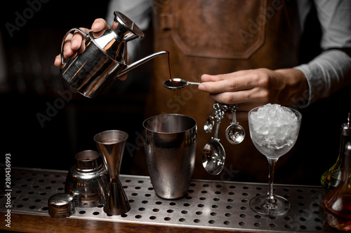 Bartender preparing drink with kettle, spoon and shaker