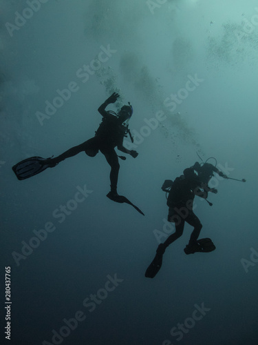 Two backlit divers in the Red Sea, off the coast of Yambu in Saudi Arabia starting a dive