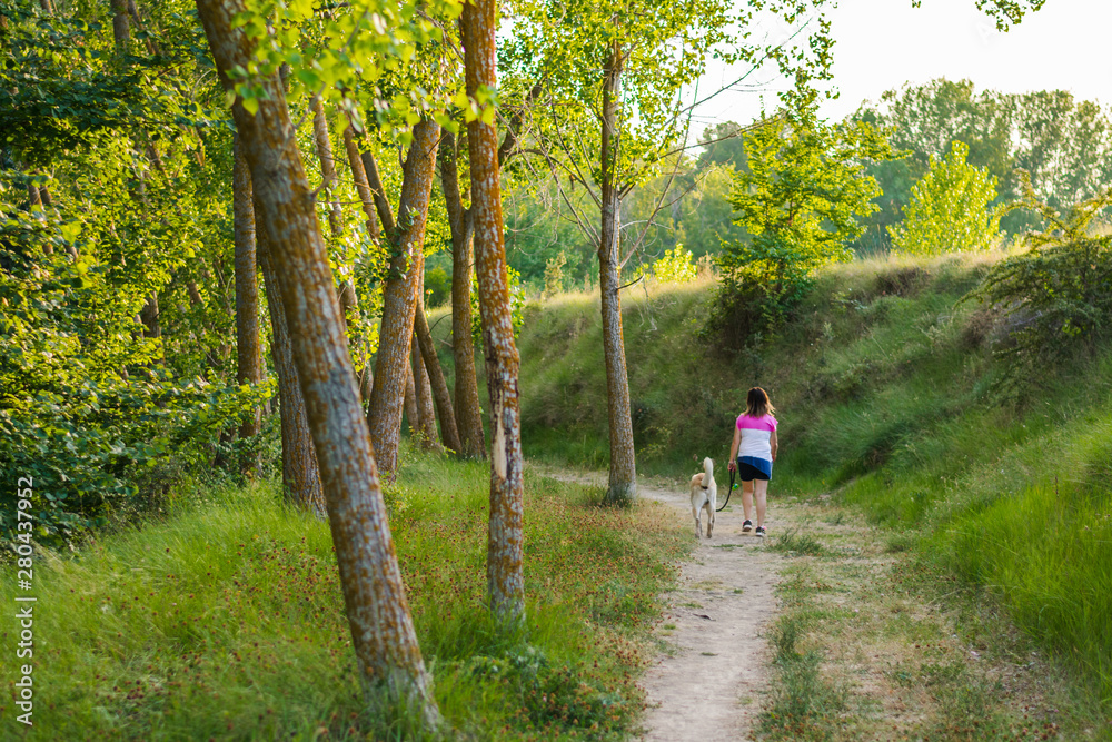 Middle-aged woman walking with her dog on a mountain path