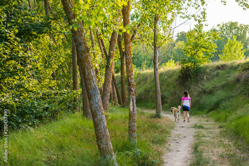 Middle-aged woman walking with her dog on a mountain path