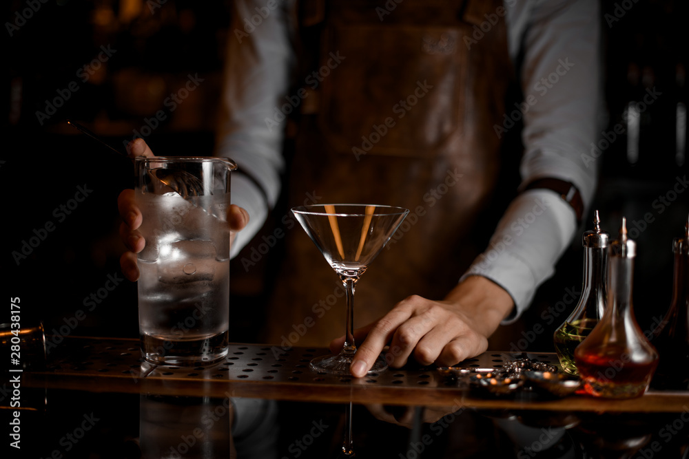 Bartender prepares to pour a martini cocktail