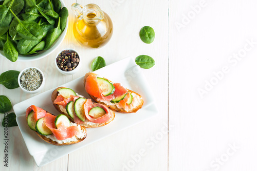 Salmon, cucumber and cream cheese bruschetta. Italian tapas, antipasti with vegetables, herbs and oil on grilled ciabatta and baguette bread. Sandwich.