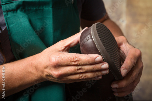 shoemaker checks a hand made shoe and its new sole