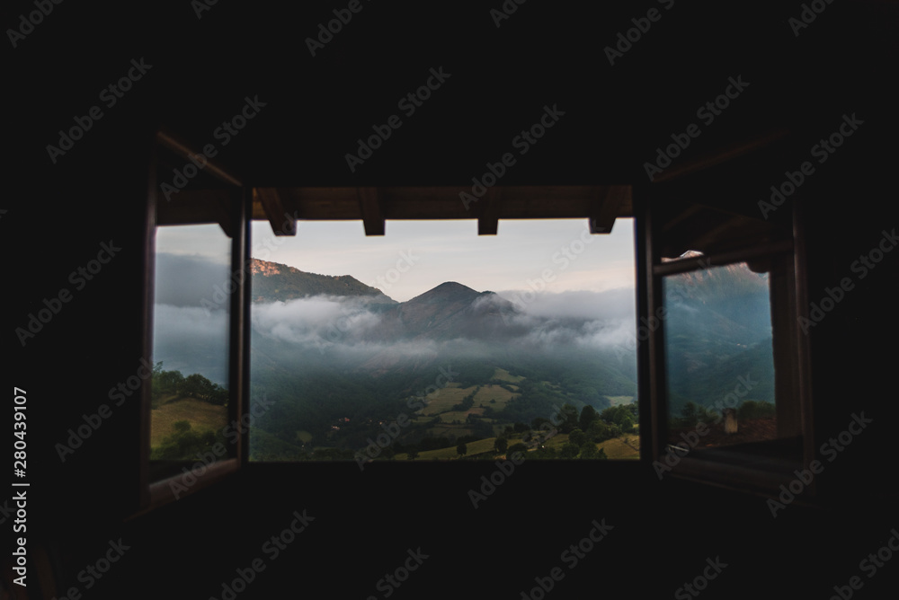 A cloudy, mountain sunrise viewed through a window in Asturias, Spain during summer. A cloudy, mountain sunrise viewed through a window in Asturias, Spain during summer.