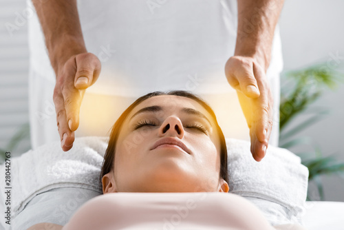 Fototapet cropped view of healer standing near patient on massage table and cleaning aura