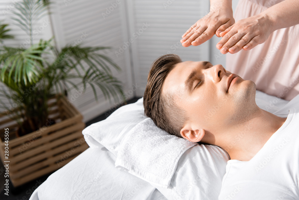 cropped view of healer standing near man with closed eyes and holding hands above his head cropped view of healer standing near man with closed eyes and holding hands above his head