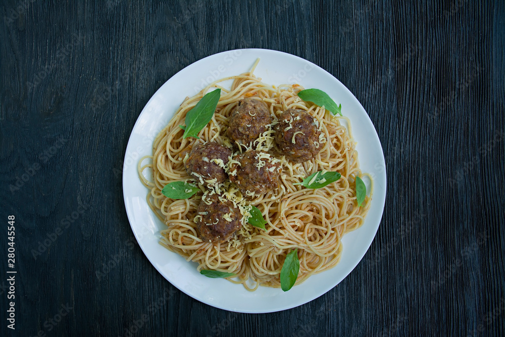 Pasta with meatballs and parsley in tomato sauce. Dark wooden background. View from above.