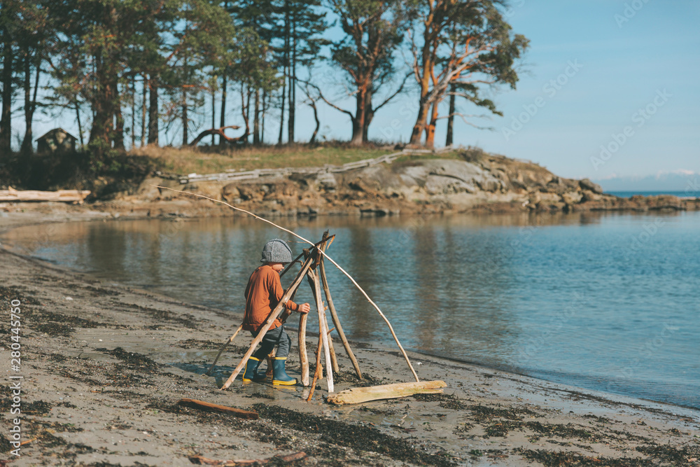 Boy playing on a the beach, building a drift wood fort Boy playing on a the beach, building a drift wood fort