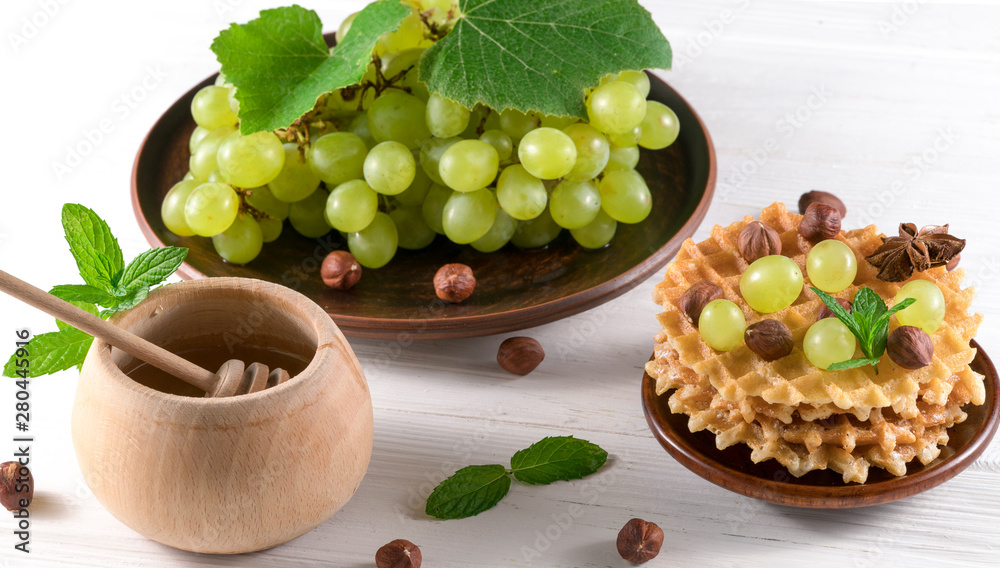 waffles honey and grapes on a white wooden background